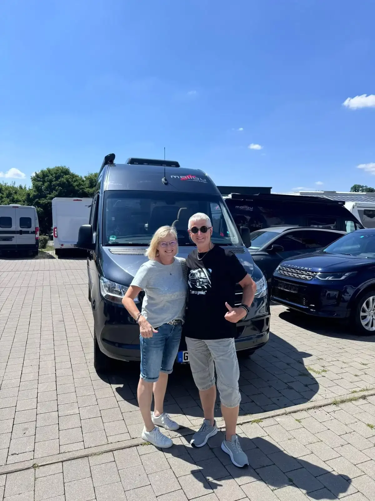 Zwei Personen stehen vor einem schwarzen Camper.